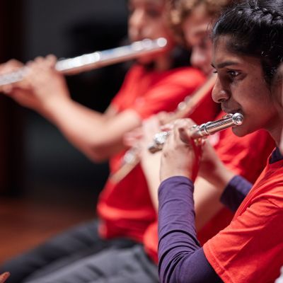 Four students play flutes in a line